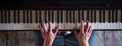 Male hands on the piano keys, top view.