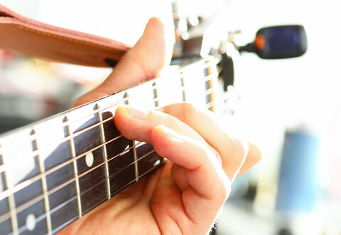 Man plays guitar, male hand holds neck guitar